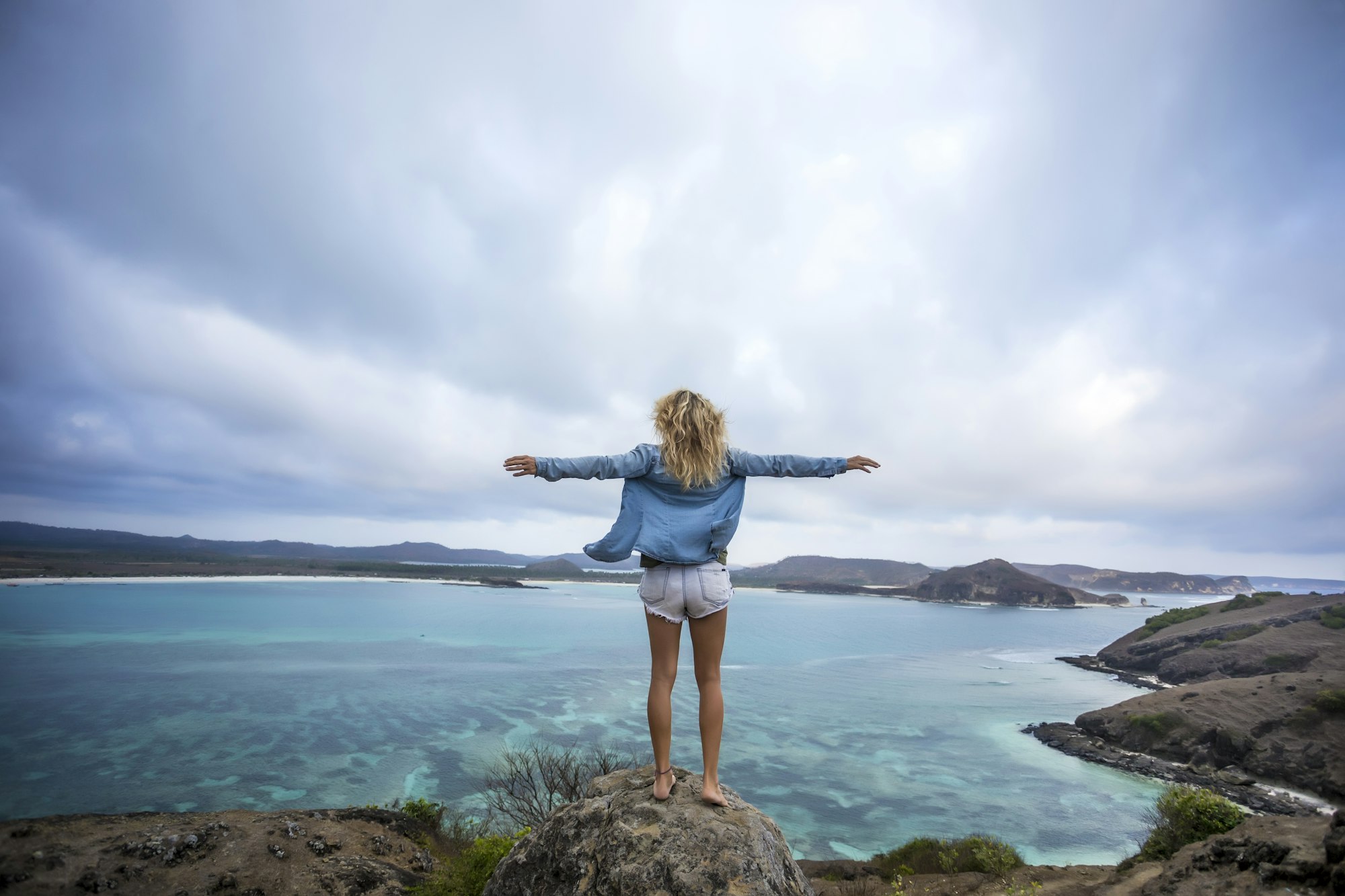 indonesia-lombok-woman-standing-at-the-coast-with-outstretched-arms.jpg